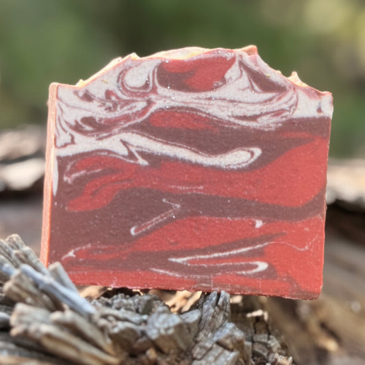 Red. white, and brown swirls called cherry almond goat milk soap bar on a natural background